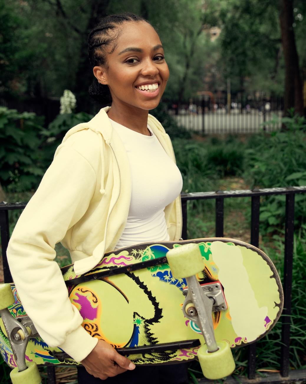 Femme souriante qui porte un skateboard dans un parc