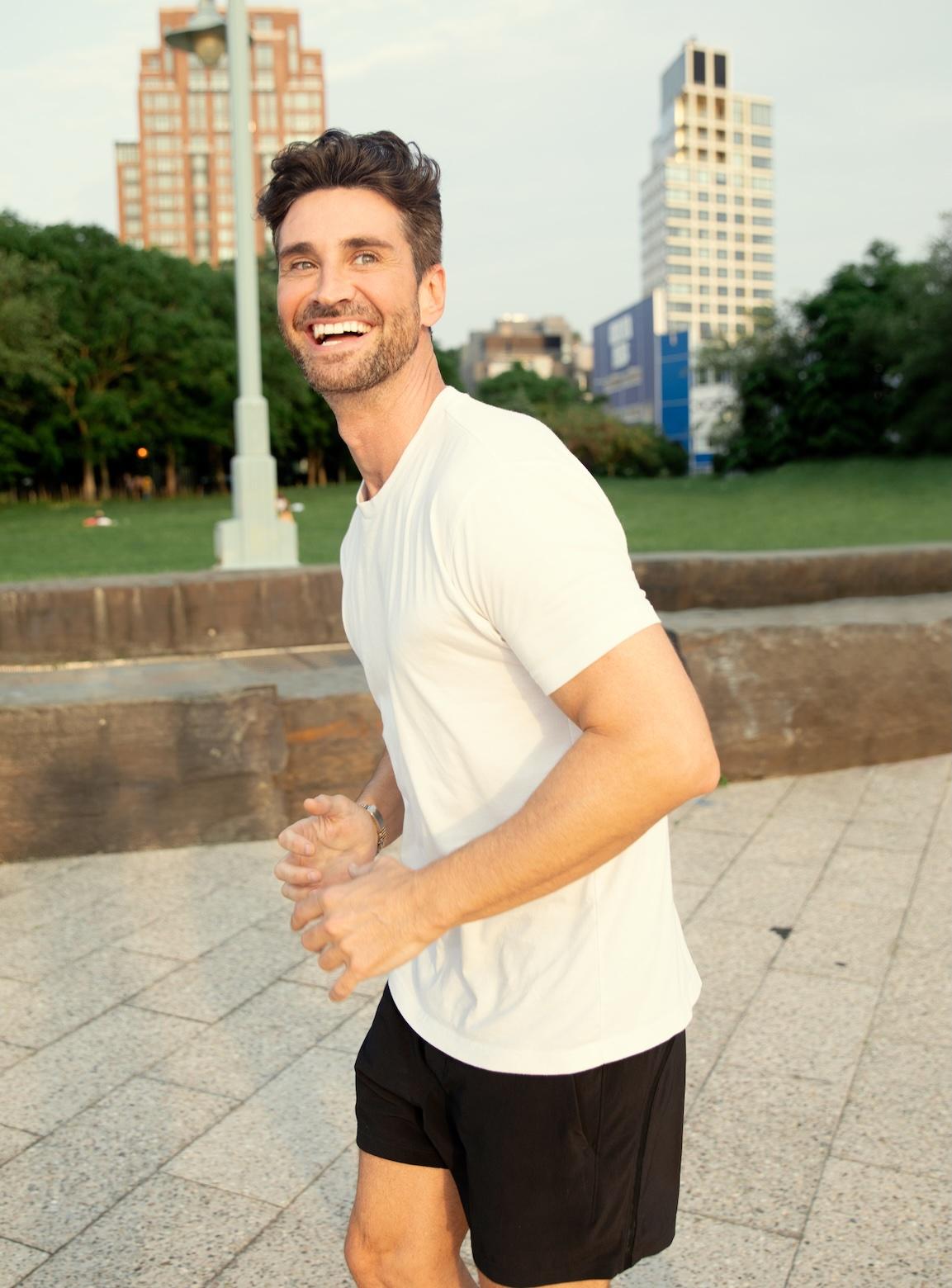 Homme souriant qui fait de la course à pied dans le parc d’une ville